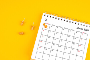 March 2026 Monthly desk calendar for 2026 year with wooden pin on yellow background.