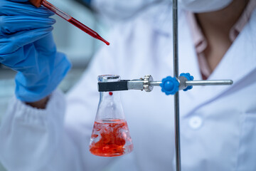 Laboratory research with blood sample in tube being dripped for medical test using liquid medicine under analysis to study results and improve scientific understanding