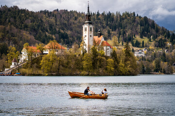 Hermosa postal del Lago de Bled, en Eslovénia, con un bote navegando frente a la iglesia Peregrinación de la Asunción de María © Javier