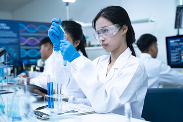 Scientist in laboratory conducting medical research using modern science and technology while taking note for doctor and clinical analysis.