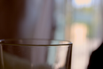 Glass cup on table in front of open window