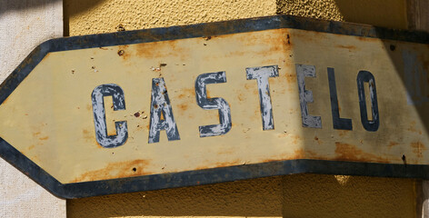Rusty signpost with the word “CASTELO” written in capital letters. ‘Castelo’ means...
