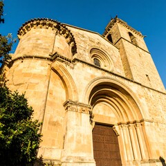 Architectural grandeur: Medieval stone church facade under a serene blue sky's radiant light