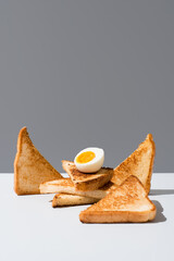 Huevo cocido sobre pan tostado desayuno sobre una mesa blanca y fondo gris	