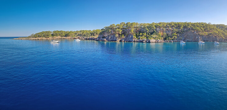 Wonderful Paradise bay of Camyuva, Kemer, Turkey. Scenery panoramic view of the coast with boats on the blue sea water. Summertime holiday seascape
