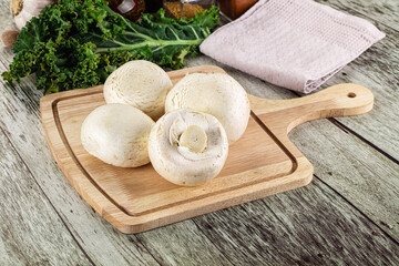 White champignon mushrooms heap over board