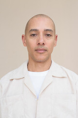 Fototapeta premium Bald Latin man face in casual shirt against beige background