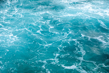 Vivid turquoise sea surface with foamy white waves and natural textures, creating a refreshing and dynamic water background. Ideal for nature, travel, and copy space.