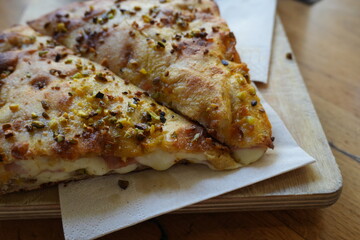 Close-up of sliced pizza with melted cheese and spices on wooden board, delicious Italian fast food, traditional baked snack for lunch, dinner, or takeaway. (