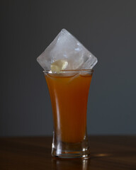 A shot glass with an ice cube and a gummi bear