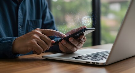 Person using smartphone with digital network overlay, next to laptop on wooden desk