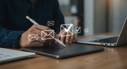 Person using stylus on tablet with email icons and checkmarks, laptop in background