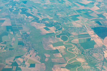 Fototapeta premium Aerial view of the Prut River winds through a patchwork of green fields in Romania and Moldova. Small settlements dot the landscape, framed by the river meandering path