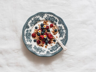 Greek yogurt with granola, raspberries and blueberries in a vintage plate on a white background