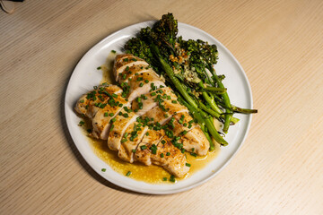 A plate of grilled chicken breast and broccolini.