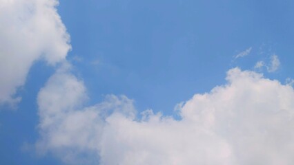 Fluffy white clouds dance across a bright blue sky, creating a serene and tranquil scene, A picturesque view of cumulus clouds painting the vast azure canvas