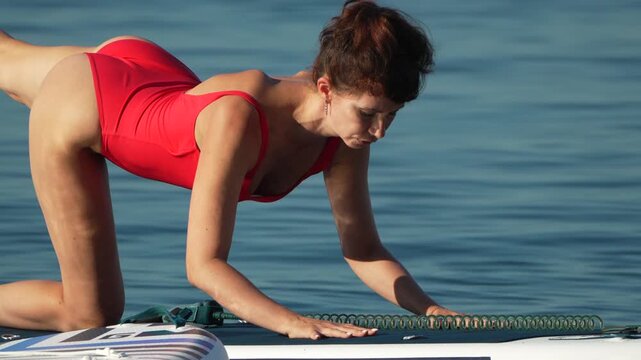 Woman yoga paddleboard, focused exercise on calm water for wellness