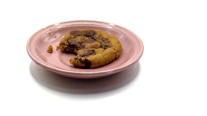 Chocolate cookies with bite marks on a pink plate isolated on a white background