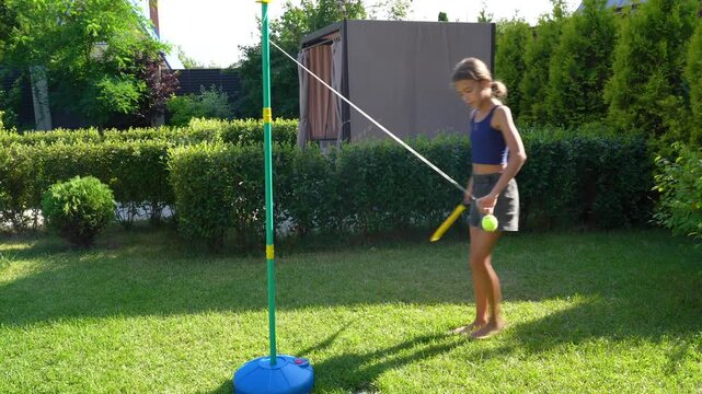 Girl plays tetherball in a sunny backyard with her dog, enjoying summer fun and exercise