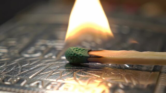 Close-up: Burning match on metallic surface, flame, fire, bright, heat, light.