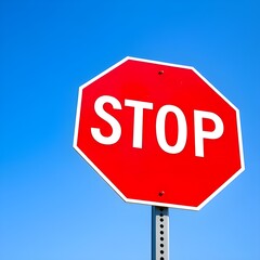 Bright red stop sign against a clear blue sky, a bold safety message for drivers and pedestrians