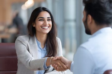 Indian Female CEO shaking hands with job applicant in modern corporate office after successful interview