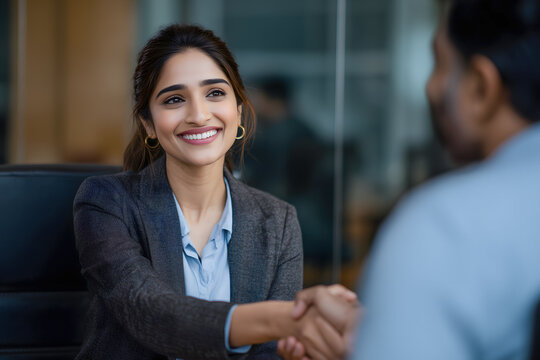 Business people handshake during job interview in sleek office with Indian female leader and applicant