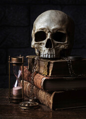 Human skull on antique books with hourglass. 
