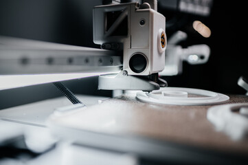 Hands of young engineer adjusting 3D printer to print resin figures