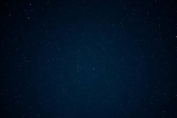 A deep dark navy blue night sky filled with countless bright white twinkling stars stretching endlessly across the celestial expanse