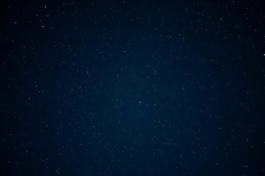 A deep dark navy blue night sky filled with countless bright white twinkling stars stretching endlessly across the celestial expanse