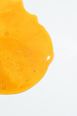 A close-up vertical shot of two hands holding a slice of toasted bread with mashed avocado. A wooden honey dipper is seen drizzling golden, viscous honey over the creamy green avocado. 