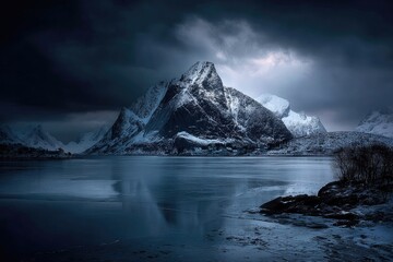 Snowy mountain peak above a frozen lake at night. Dramatic clouds and icy reflection