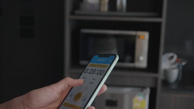 A close-up of a smartphone displaying a timer app amidst a contemporary kitchen environment. The image captures the blend of technology and daily cooking tasks.