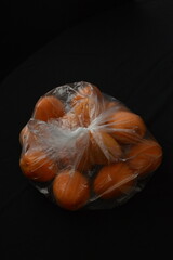 Close up apricots in plastic bag, black background, separated, negative space, copy space,