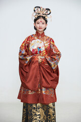 Obraz premium A cute girl wearing a Ming Dynasty phoenix coronet and embroidered robe against a white background.