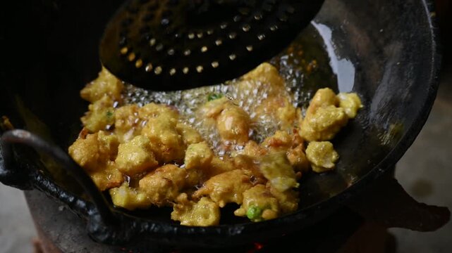 Onion pakora frying in iron pen. This is a popular street food in Indian subcontinent. Onion which are coated in seasoned&nbsp;spicy gram flour&nbsp;batter and deep fried. It originated in India.