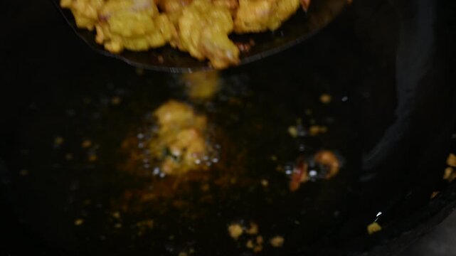 Onion pakora frying in iron pen. This is a popular street food in Indian subcontinent. Onion which are coated in seasoned&nbsp;spicy gram flour&nbsp;batter and deep fried. It originated in India.