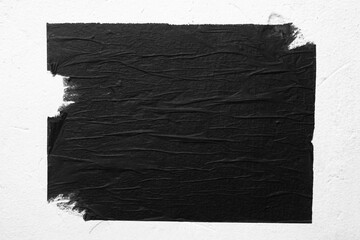 A black torn poster is taped to a white wall.