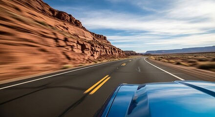 Driving on a desert highway past red rock formations under a blue sky road landscape