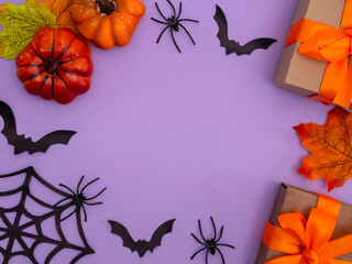 Halloween holiday decorations including gift box, pumpkins, spiders, bats on purple background