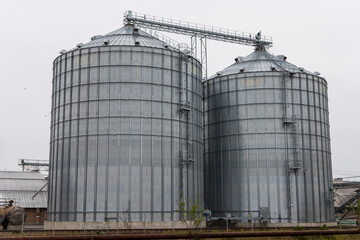 Metal silos stand prominently at an agricultural site, designed for efficient grain storage under cloudy skies