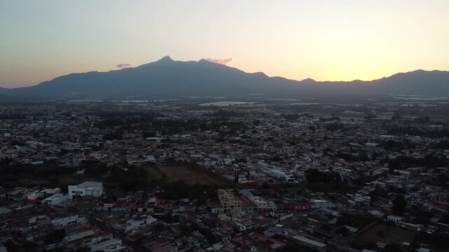 Drone footage over Ciudad Guzman city during sunset, surrounded by mountains in Mexico