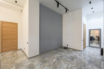Modern interior featuring marble floors, a gray accent wall, and wooden doors. Sleek lighting adds...