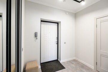 Minimalist hallway. White door, mirror with black stripes, beige stool. Gray floor. Clean and modern design