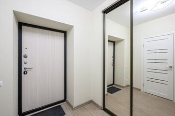 hallway view with doors, a mirror closet, and light wood flooring