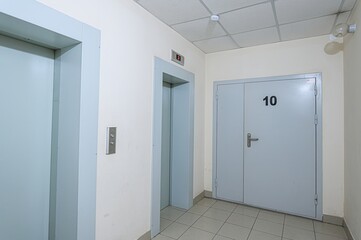 hallway features two elevator doors and a door numbered 10. The interior is functional, with tiled flooring and a drop ceiling