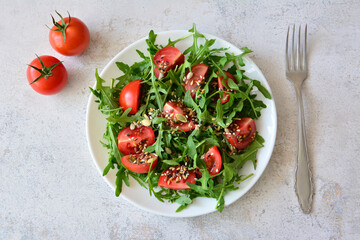 Tomato and Arugula Salad with Seeds in white plate flat lay