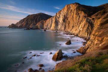 Coastal cliffs meet a tranquil ocean at sunset