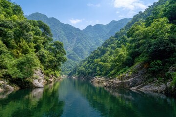 Serene river flows through lush green mountain valley under a bright blue sky